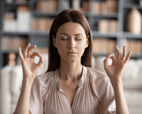 Mujer joven haciendo un gesto meditativo con los ojos cerrados.